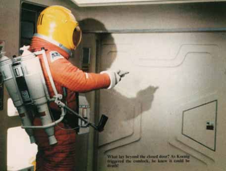Caption: What lay beyond the closed door? As Koenig triggered the comlock, he knew it could be death!, Picture: Spacesuited Koenig pointing comlock at door